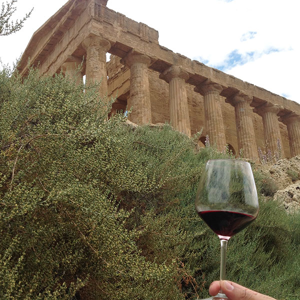 Un calice di Nero d'Avola davanti al Tempio della Concordia ad Agrigento