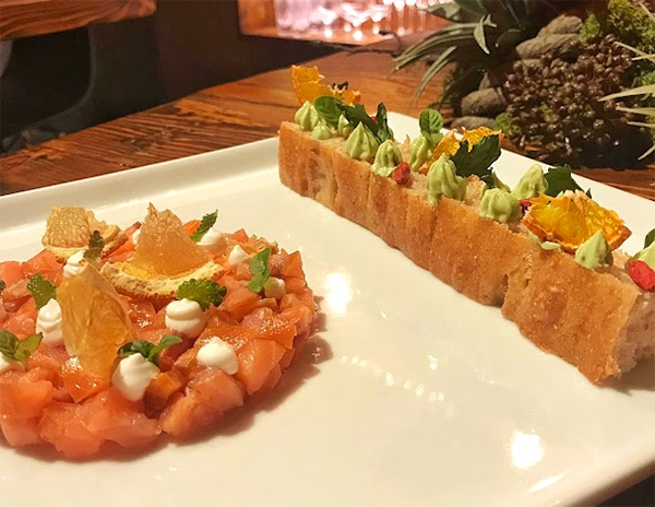 Il Salmone Affumicato: salmone delle Isole Lofoten affumicato a freddo con bacche di ginepro, crema di yogurt, focaccia ai cereali e albicocca con burro alle erbe