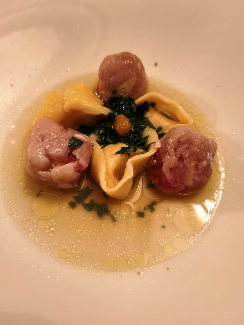 Tortelli di aragosta e dentice accompagnati da fagottini di maiale, brodo ristretto di bovino ed essenza di mandarino